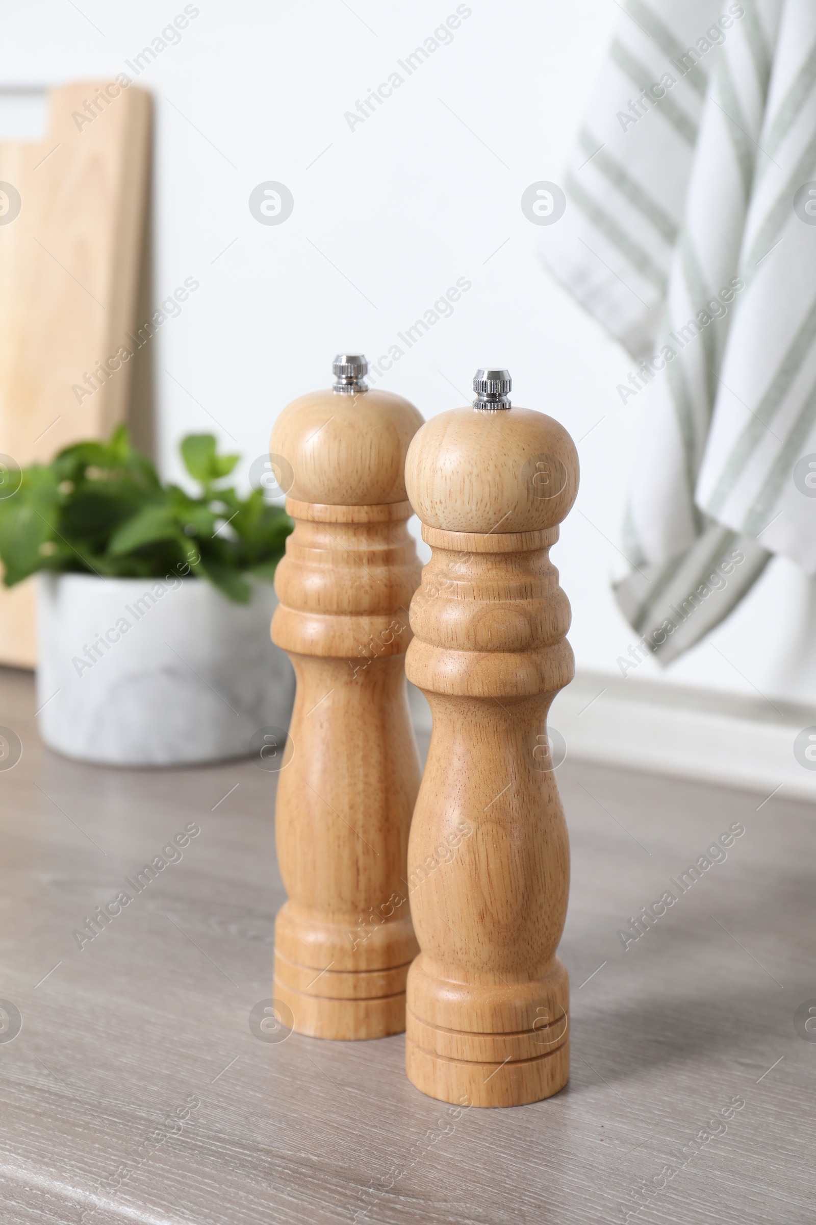 Photo of Salt and pepper mills on grey wooden counter indoors, closeup