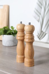 Photo of Salt and pepper mills on grey wooden counter indoors, closeup