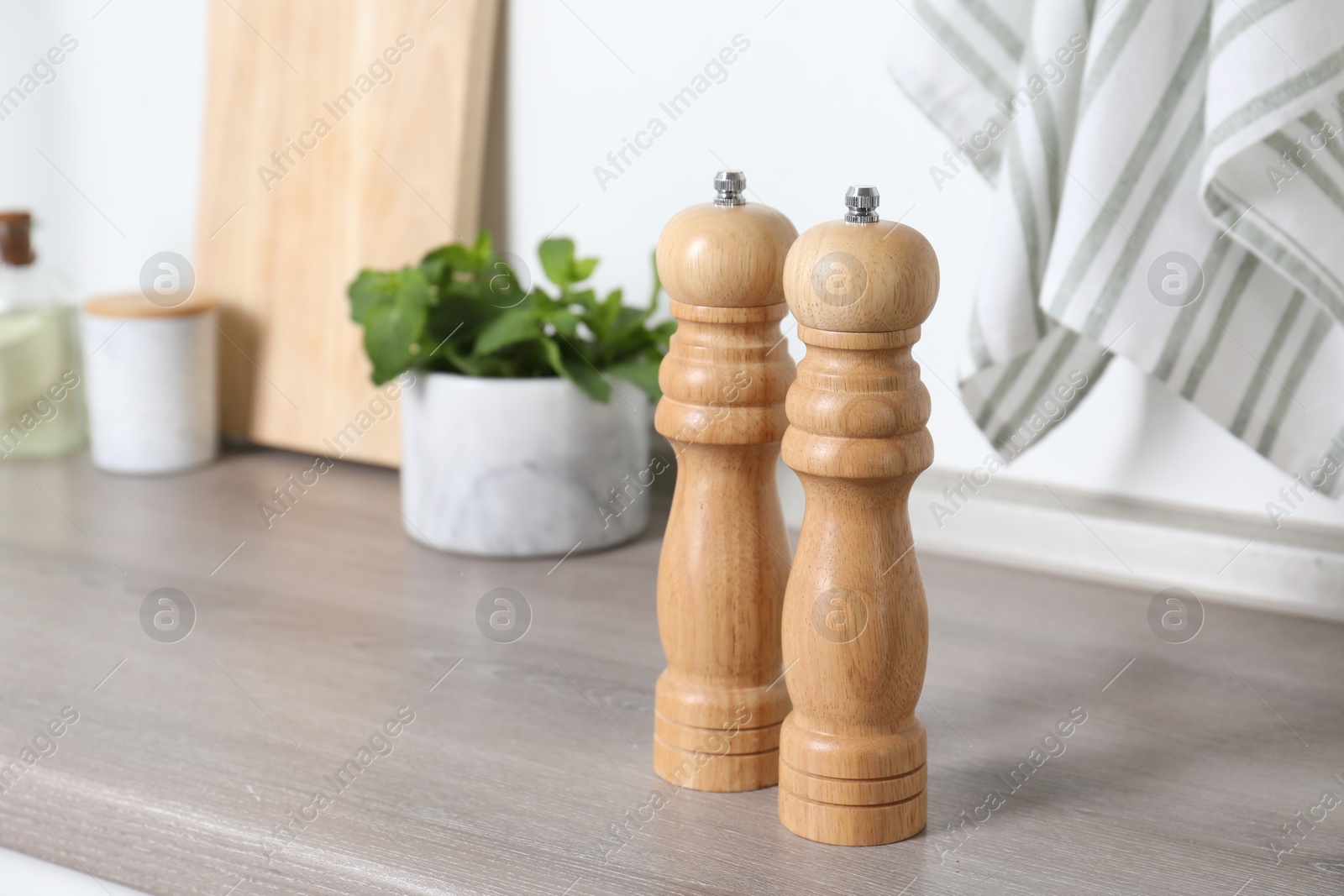 Photo of Salt and pepper mills on grey wooden counter indoors, closeup. Space for text