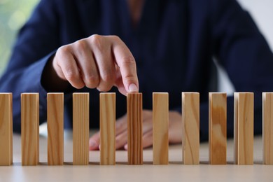 Photo of Risk. Woman pointing at domino tale at table, closeup