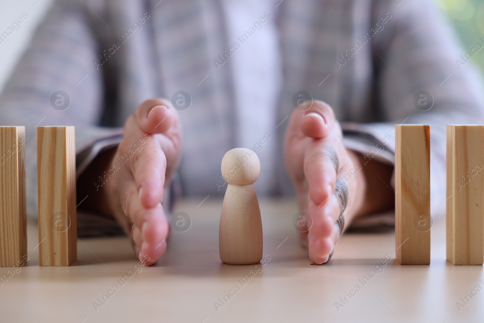 Photo of Risk. Woman stopping domino effect to protect wooden figure at table, closeup