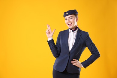 Photo of Beautiful stewardess showing something on yellow background. Space for text
