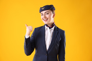 Photo of Beautiful stewardess pointing at something on yellow background