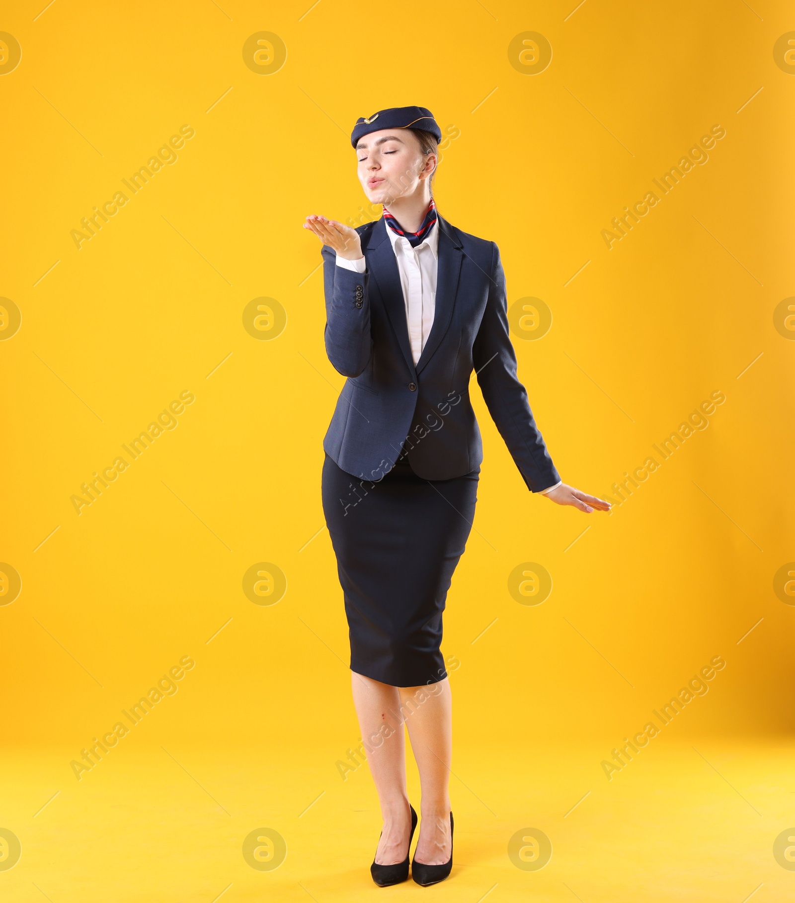 Photo of Stewardess blowing air kiss on yellow background