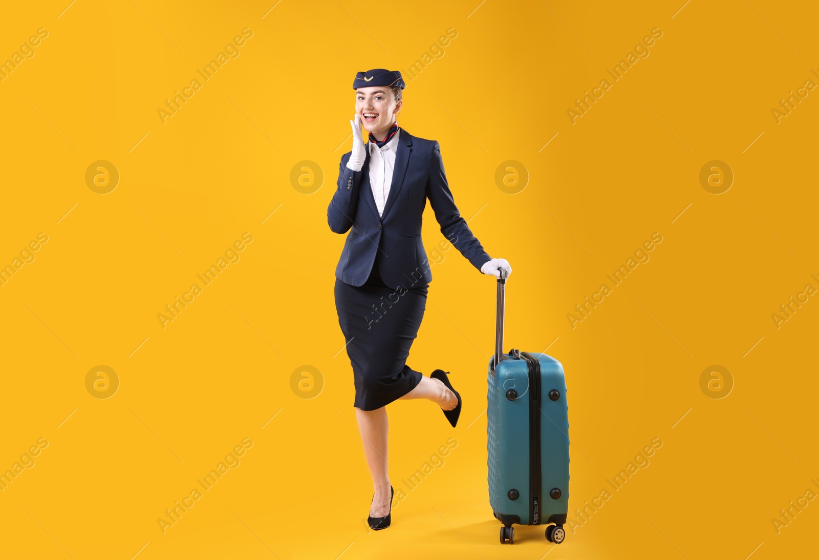 Positive stewardess with suitcase on yellow background Photo of Positive stewardess with suitcase on yellow background