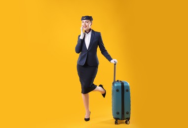Photo of Positive stewardess with suitcase on yellow background
