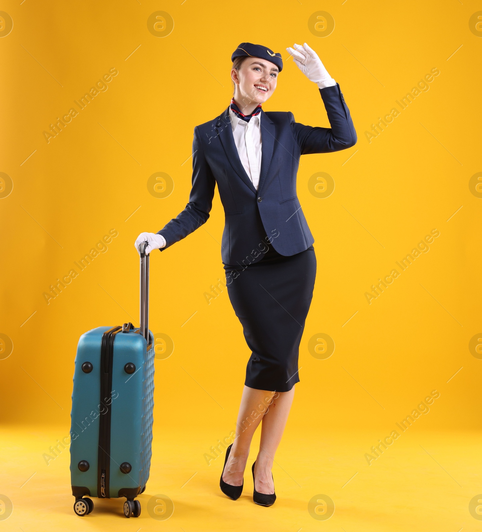 Photo of Positive stewardess with suitcase on yellow background