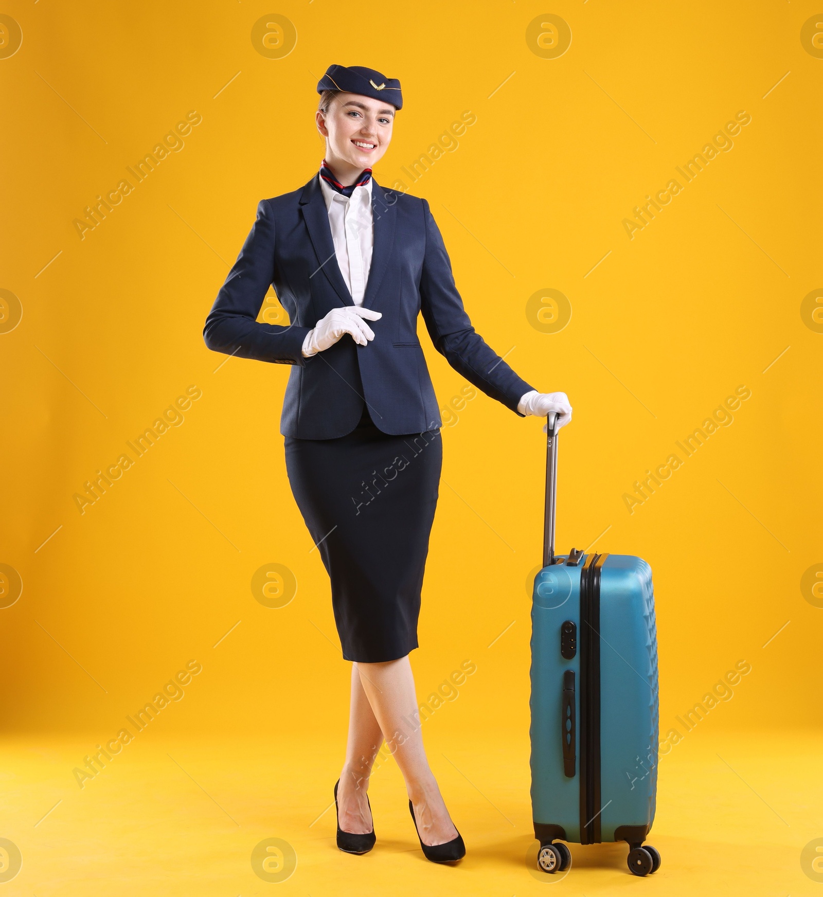Photo of Positive stewardess with suitcase on yellow background