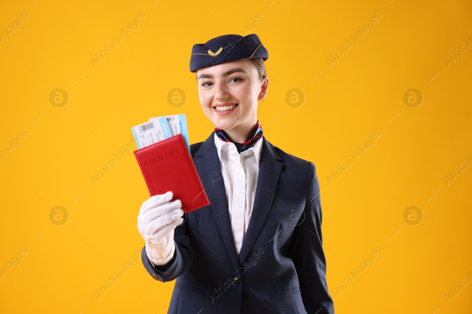 Photo of Smiling stewardess with passport and tickets on yellow background