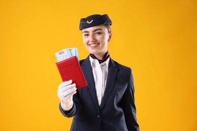 Photo of Smiling stewardess with passport and tickets on yellow background