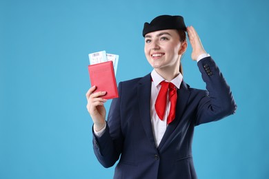 Photo of Smiling stewardess with passport and tickets on light blue background