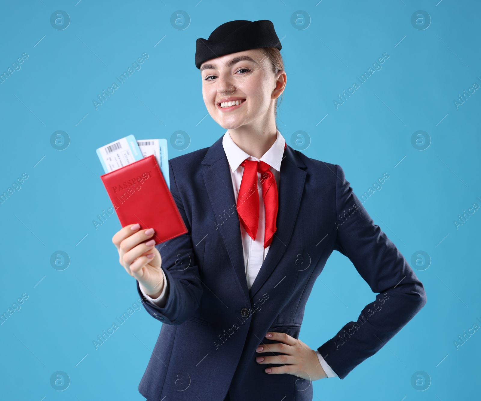 Photo of Smiling stewardess with passport and tickets on light blue background