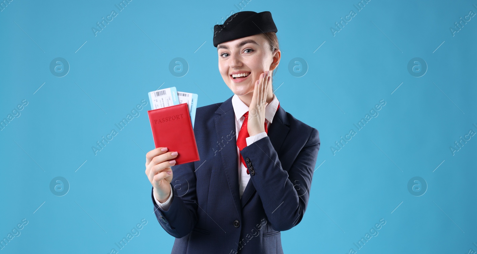 Photo of Smiling stewardess with passport and tickets on light blue background