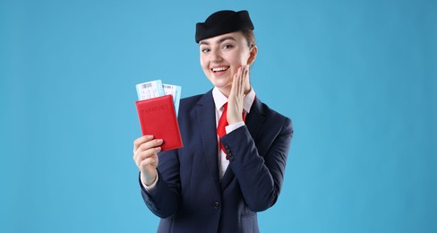 Photo of Smiling stewardess with passport and tickets on light blue background