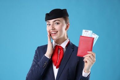 Photo of Smiling stewardess with passport and tickets on light blue background