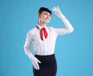 Photo of Charming stewardess in uniform on light blue background