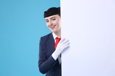 Photo of Stewardess and blank poster on blue background. Space for text