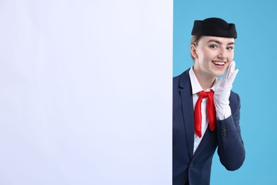 Photo of Stewardess and blank poster on blue background. Space for text
