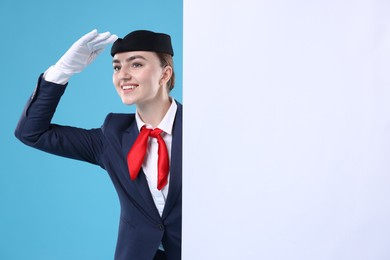 Photo of Stewardess and blank poster on blue background. Space for text