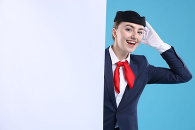 Photo of Stewardess and blank poster on blue background. Space for text