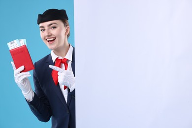 Photo of Stewardess with passport, tickets and blank poster on blue background. Space for text