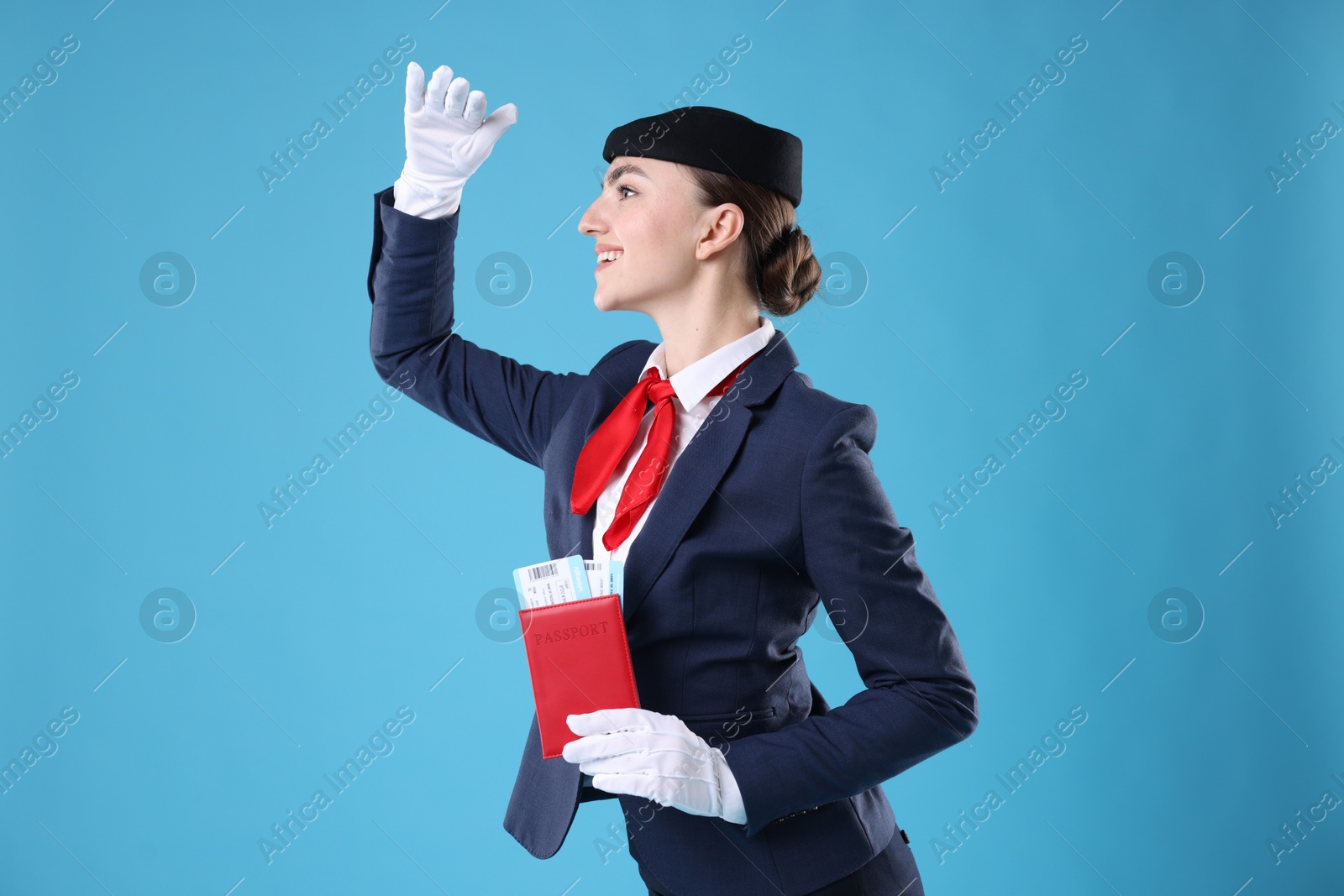 Photo of Smiling stewardess with passport and tickets on light blue background