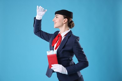 Photo of Smiling stewardess with passport and tickets on light blue background