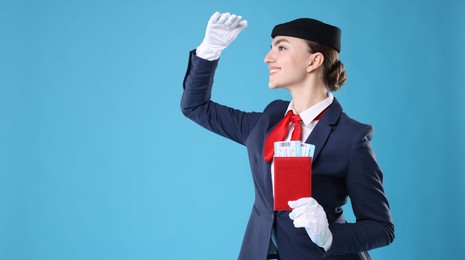 Photo of Smiling stewardess with passport and tickets on light blue background. Space for text