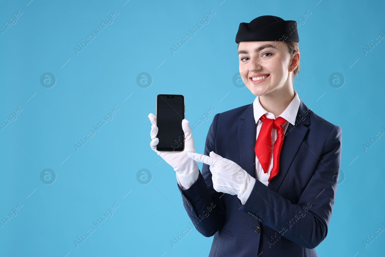 Photo of Beautiful stewardess with smartphone on light blue background. Space for text