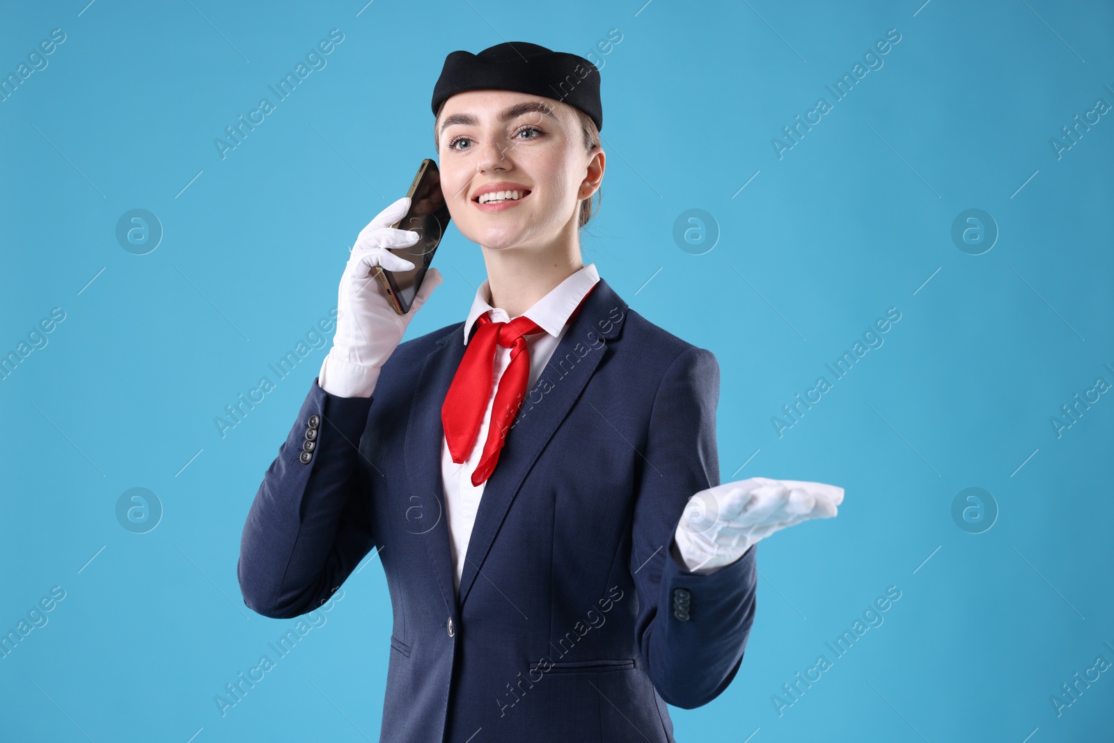 Photo of Beautiful stewardess talking on phone against light blue background