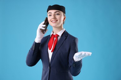 Photo of Beautiful stewardess talking on phone against light blue background