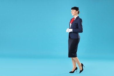 Photo of Charming stewardess in uniform on light blue background. Space for text