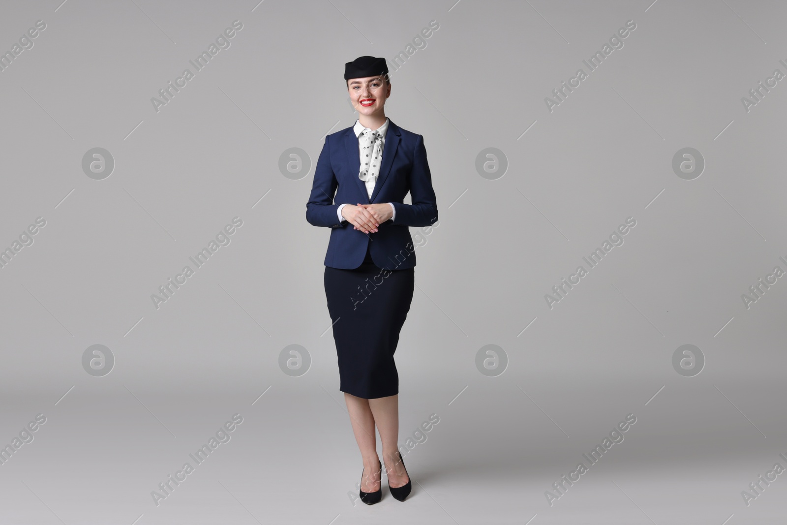 Photo of Charming stewardess in uniform on light grey background