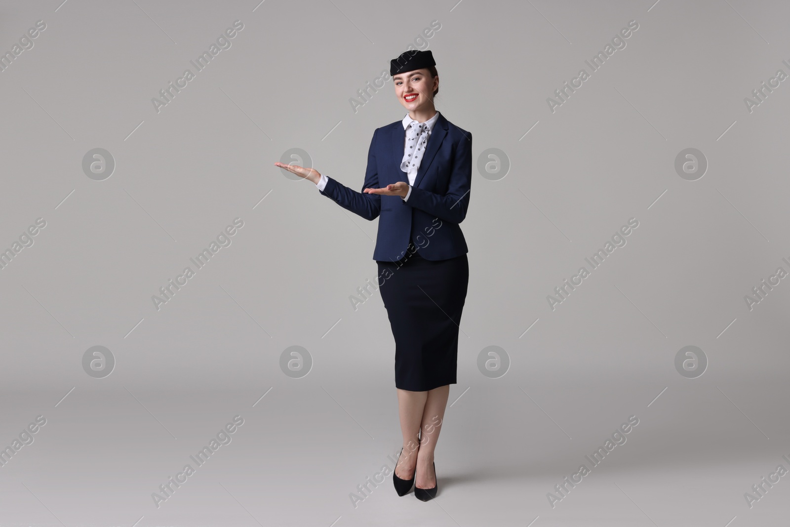 Photo of Beautiful stewardess showing something on light grey background