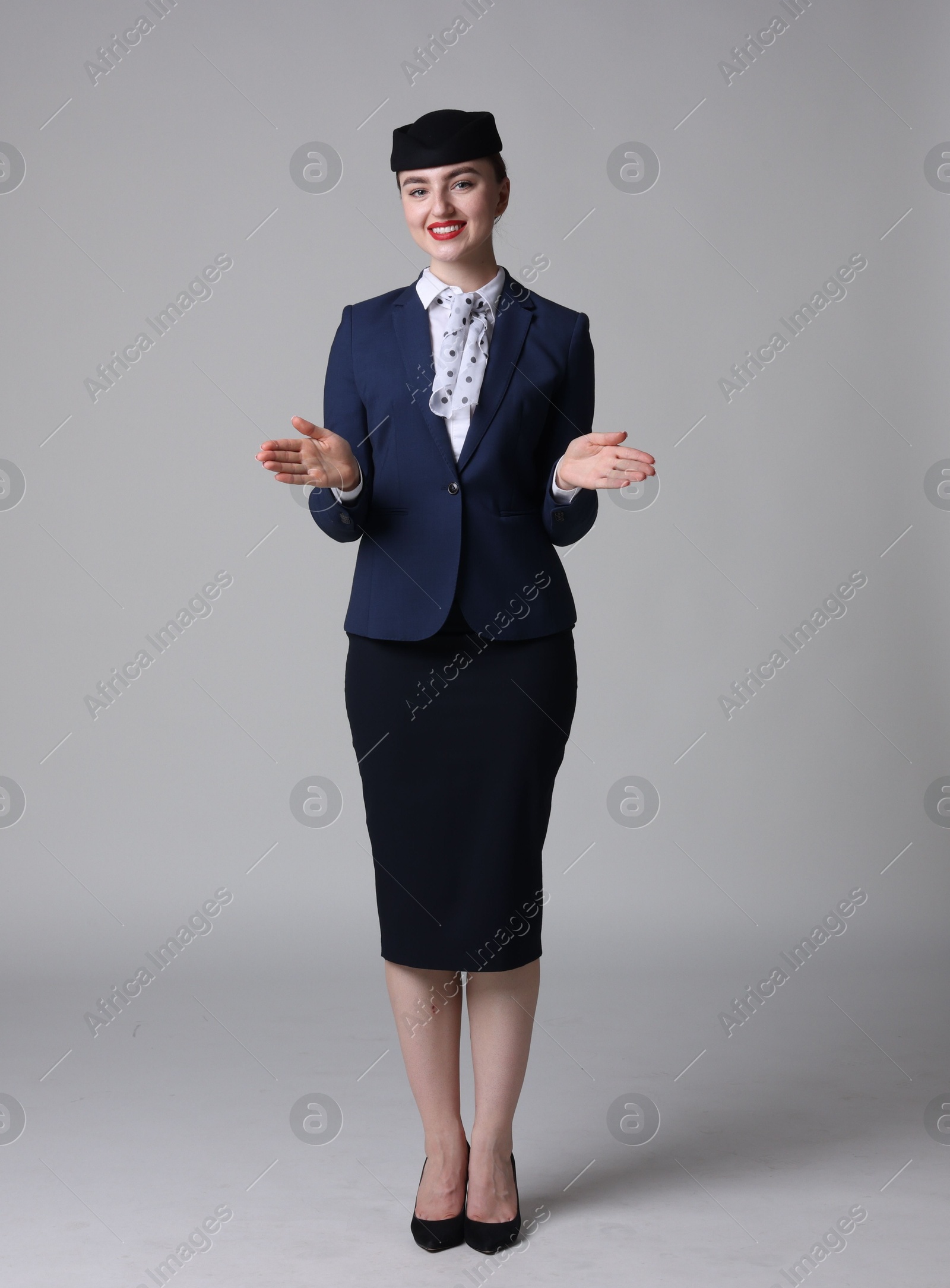 Photo of Positive stewardess doing pre-flight safety briefing on light grey background