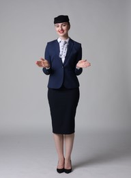 Photo of Positive stewardess doing pre-flight safety briefing on light grey background