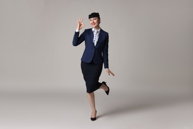 Photo of Charming stewardess showing okay gesture on light grey background