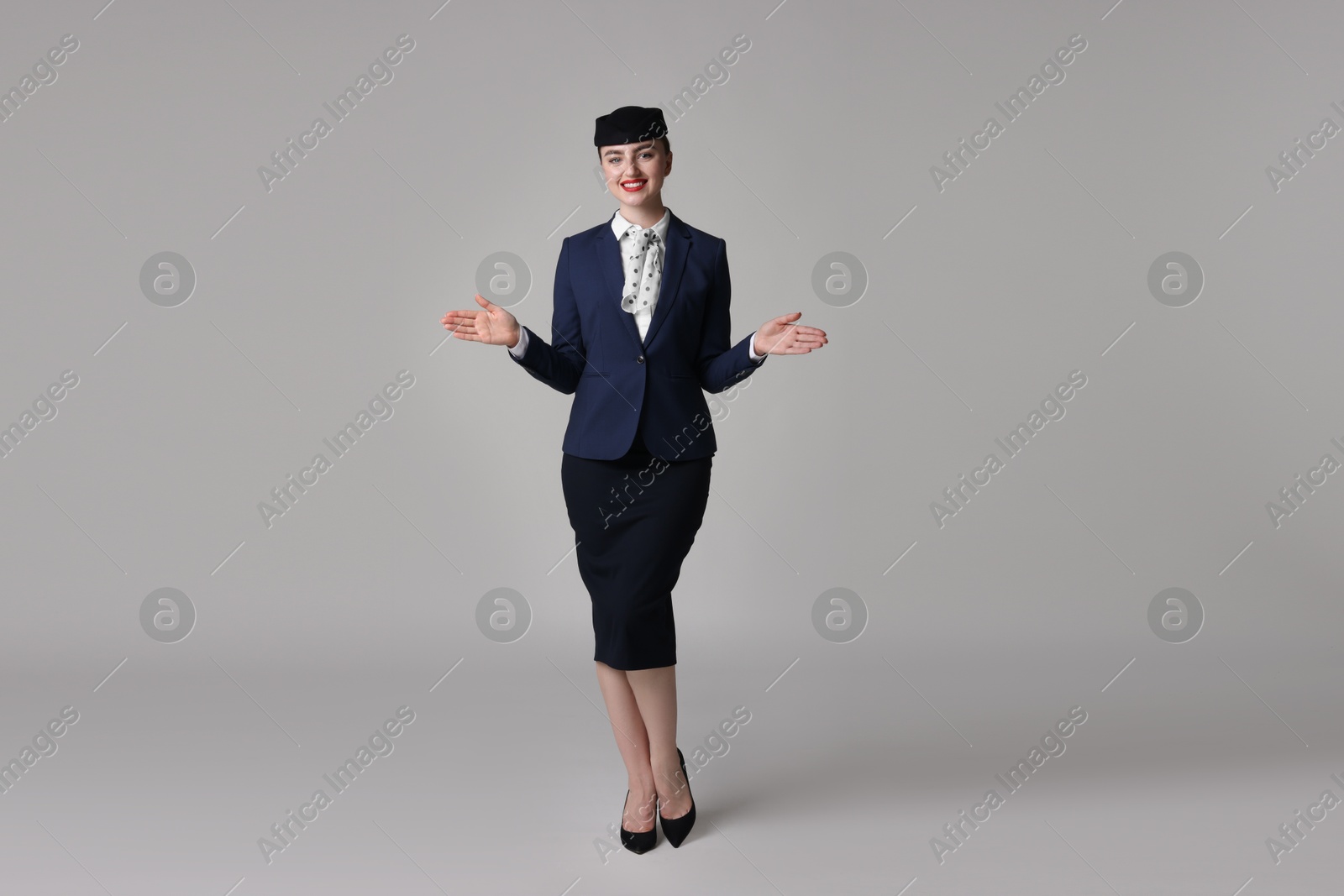Photo of Positive stewardess doing pre-flight safety briefing on light grey background
