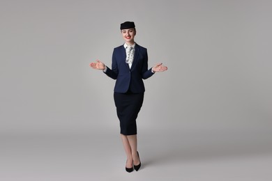 Photo of Positive stewardess doing pre-flight safety briefing on light grey background