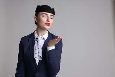 Photo of Stewardess blowing air kiss on light grey background. Space for text