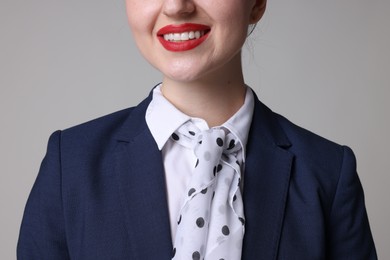 Photo of Charming stewardess in uniform on light grey background, closeup