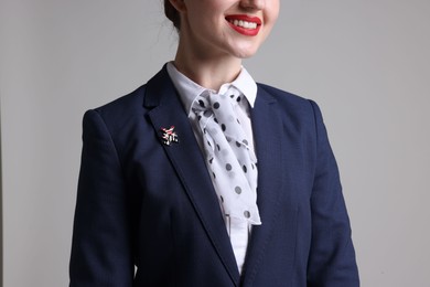 Photo of Charming stewardess in uniform on light grey background, closeup
