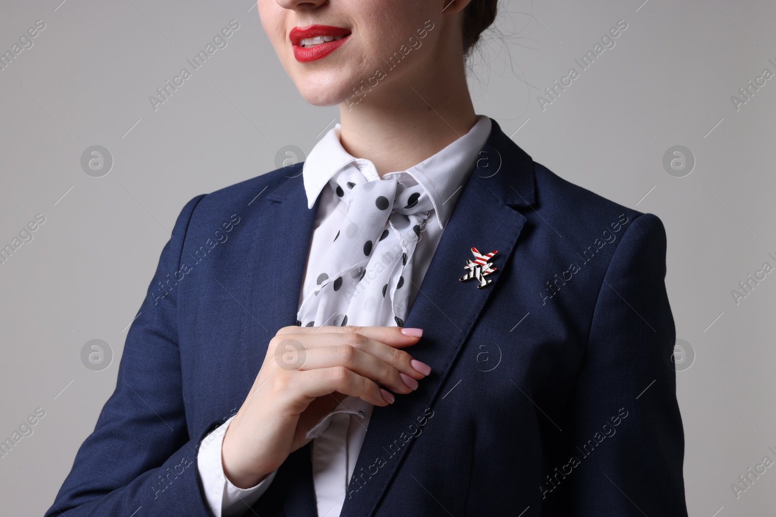 Photo of Charming stewardess in uniform on light grey background, closeup