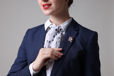Photo of Charming stewardess in uniform on light grey background, closeup