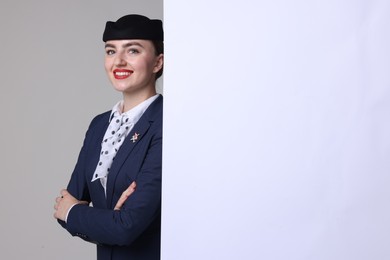 Photo of Stewardess and blank poster on grey background. Space for text