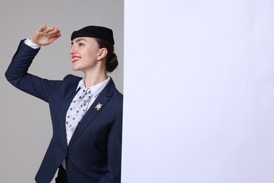 Photo of Stewardess and blank poster on grey background. Space for text