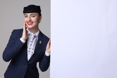 Photo of Stewardess and blank poster on grey background. Space for text