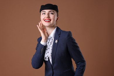 Photo of Charming stewardess in uniform on brown background