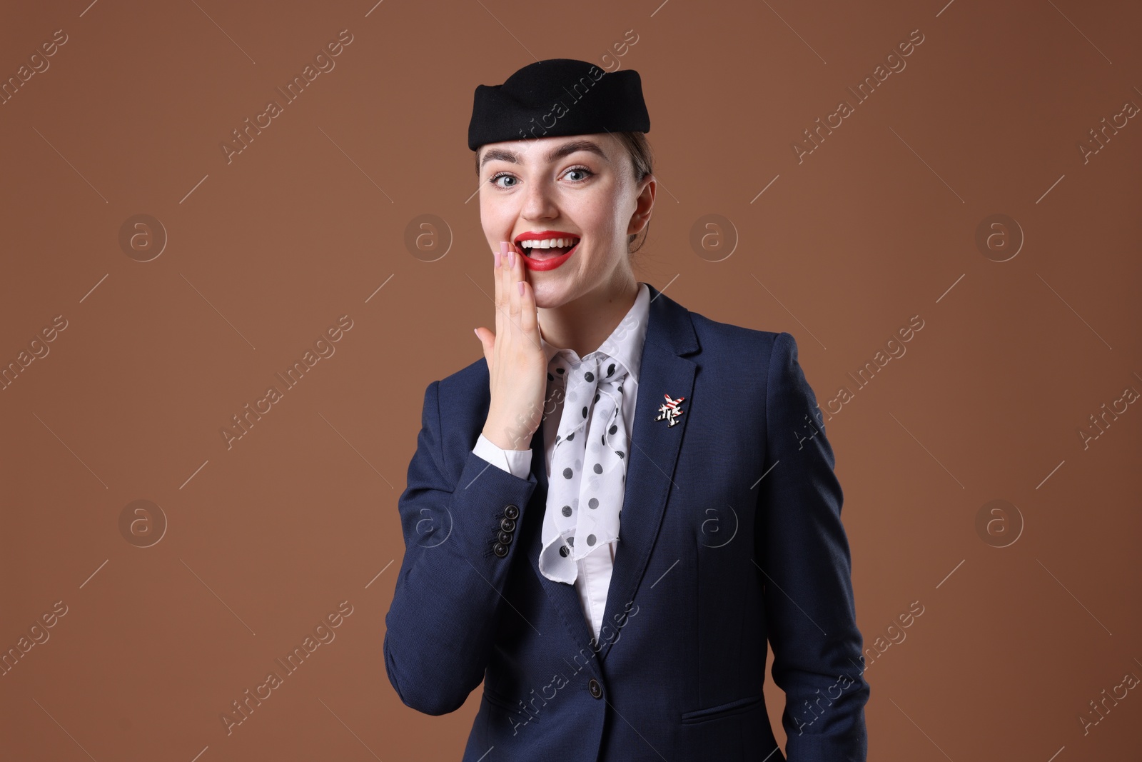 Photo of Charming stewardess in uniform on brown background