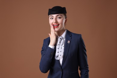 Photo of Charming stewardess in uniform on brown background